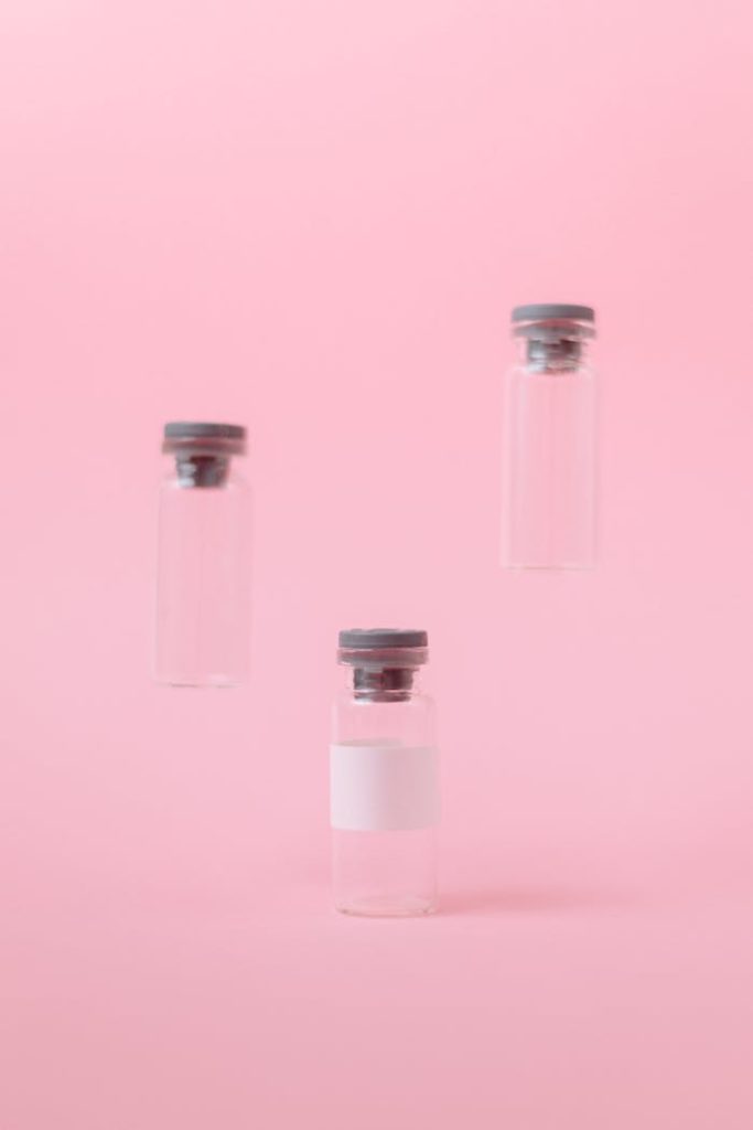 Three empty medical vials floating on a soft pink background.